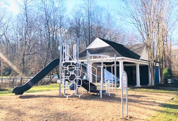 A playground with a slide and a sign in front of a building.