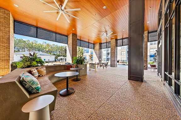 A modern outdoor seating area with a wooden ceiling and concrete flooring.