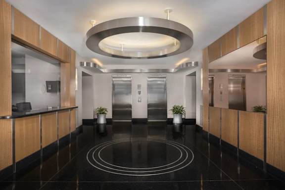 A modern hallway with a black marble floor and wooden panels on the walls.