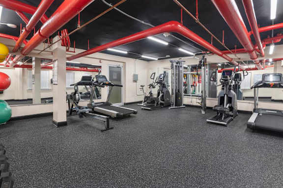 A gym with a variety of equipment including treadmills, weights, and exercise machines.