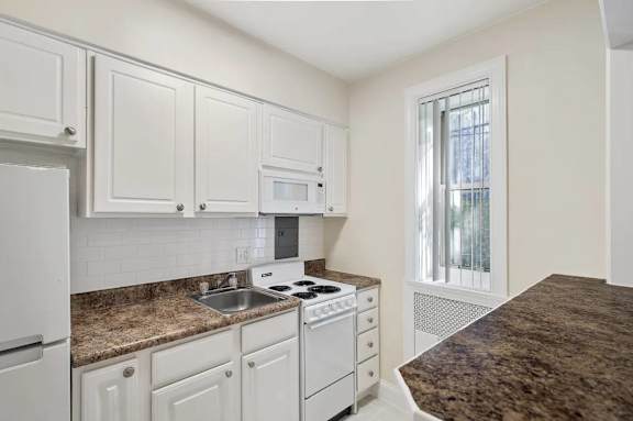 A kitchen with white cabinets and a granite countertop.