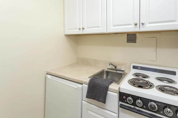 Small kitchen with electric stove and sink at Empire Apartments, Washington, DC