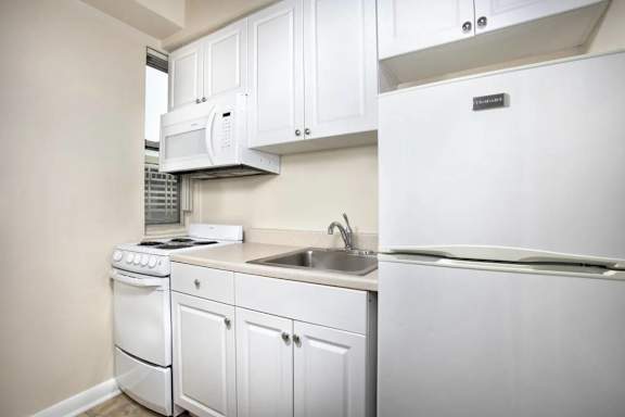 Galley kitchen with white cabinetry and microwave at Empire Apartments, Washington