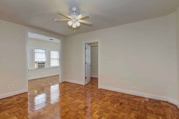 A room with a ceiling fan and wooden flooring.