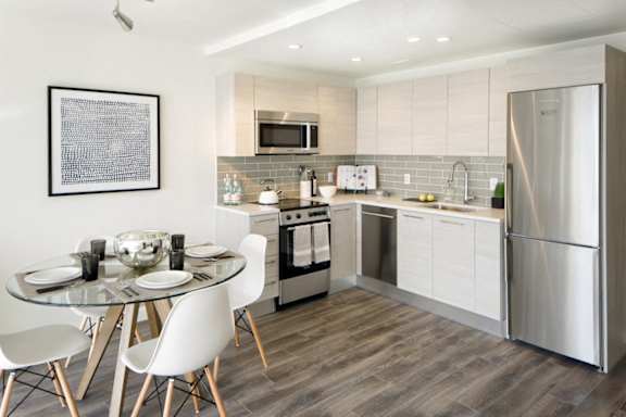 Compact kitchen with white cabinets and gray backsplash at 1305 Dock Apartments, Maryland, 21231