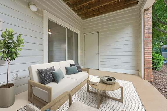 A white couch with blue pillows sits on a patio with a coffee table.