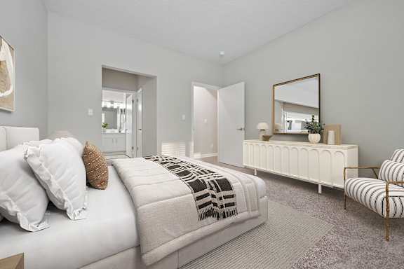 A bedroom with a bed, a chair, and a mirror.