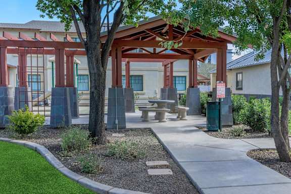 A covered outdoor seating area with a table and chairs.