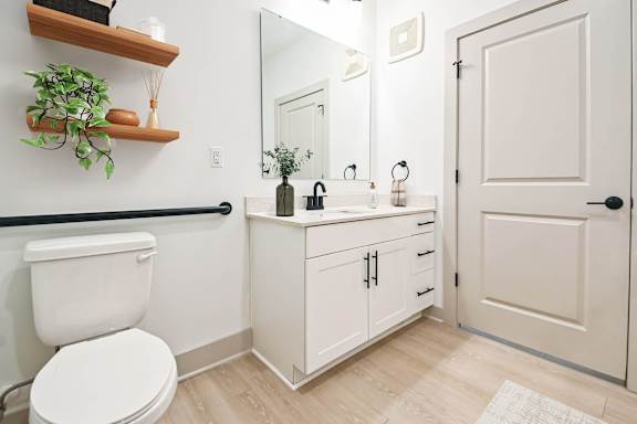 a white bathroom with a toilet and a sink at Metropolitan at the Riverwalk, Wilmington, NC