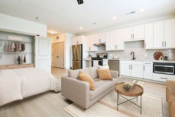 a white living room with a couch and a kitchen at Metropolitan at the Riverwalk, Wilmington, NC