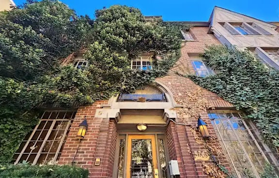 A building with a yellow door and windows covered in greenery.