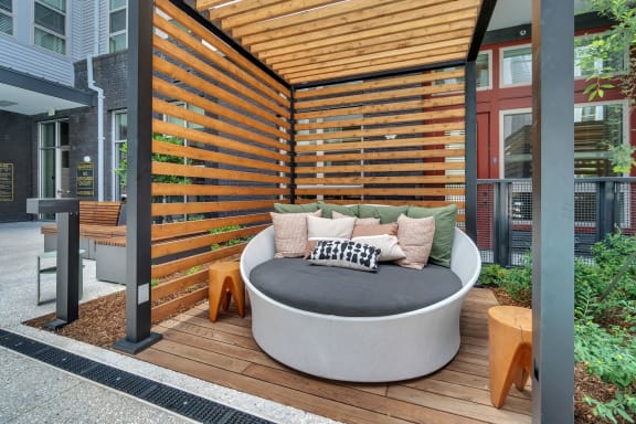 a round couch on a deck with a wooden privacy fence