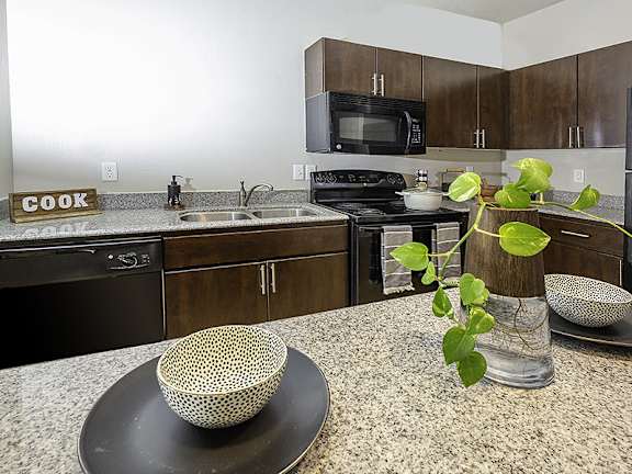 A kitchen with a black stove and wooden cabinets.