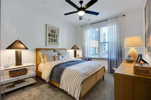 A bedroom with a bed, nightstands, and a ceiling fan.