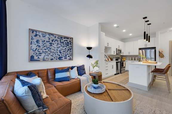 A modern living room with a brown leather couch and a blue and white abstract painting on the wall.