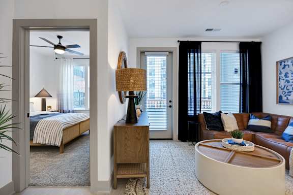 A bedroom with a bed, a couch, and a table with a plant on it.