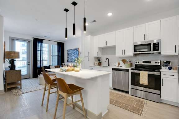 A modern kitchen with a white island and wooden chairs.