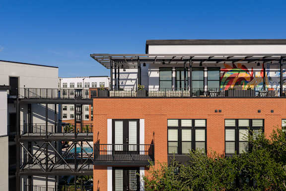 A red brick building with a balcony and a mural on the side.