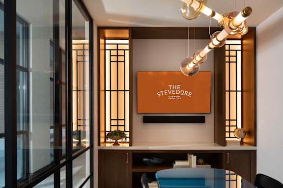 A modern office space with a glass table and a hanging light fixture.