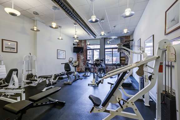 A gym with a variety of equipment including treadmills, weights, and exercise machines  a room with tables and chairs and a computer in a room at Tindeco Wharf, Baltimore Maryland