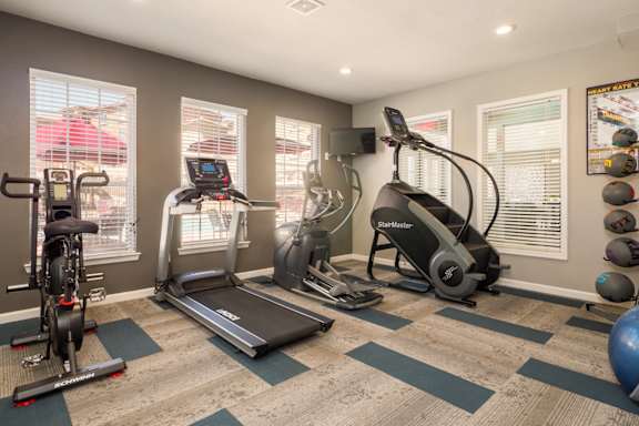 A home gym with a treadmill, elliptical trainer, and stationary bike at West Park Apartments, Albuquerque, NM, 87114