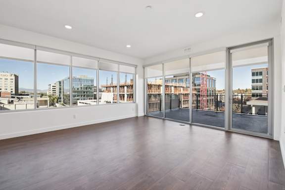 A large empty room with a view of the city outside the windows.
