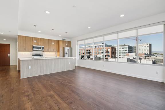 A spacious kitchen with wooden floors and a large window overlooking the city.