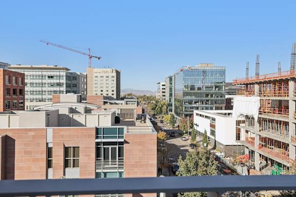 A construction site is visible in the distance behind a building with a balcony.