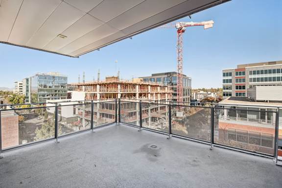 A construction site is visible from a balcony with a white ceiling.