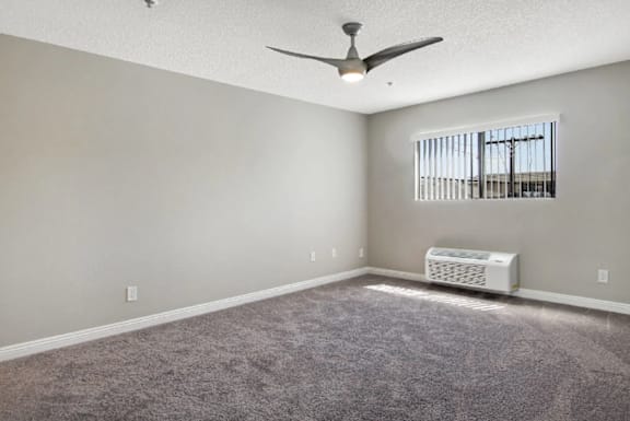 A room with a ceiling fan and a window with blinds.