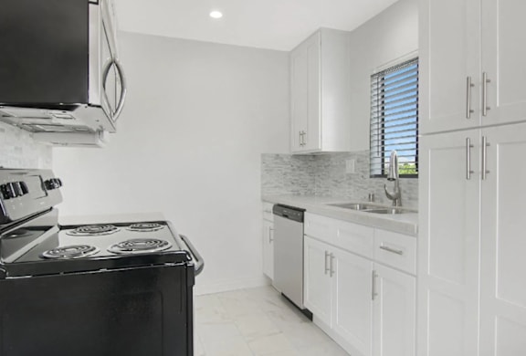 A modern kitchen with white cabinets and a black stove top.