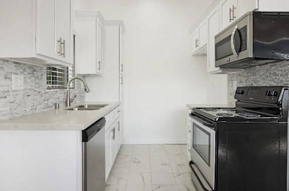 A kitchen with black appliances and white cabinets.