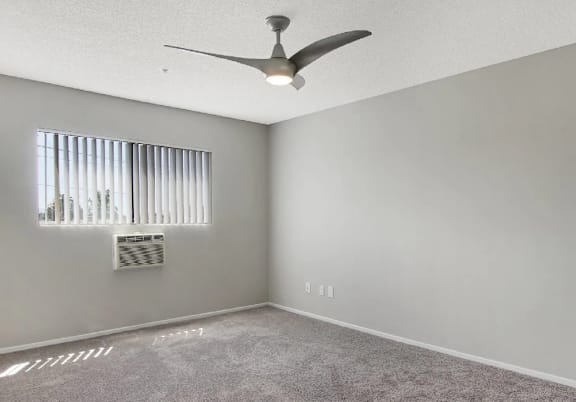 A room with a ceiling fan and a window with blinds.