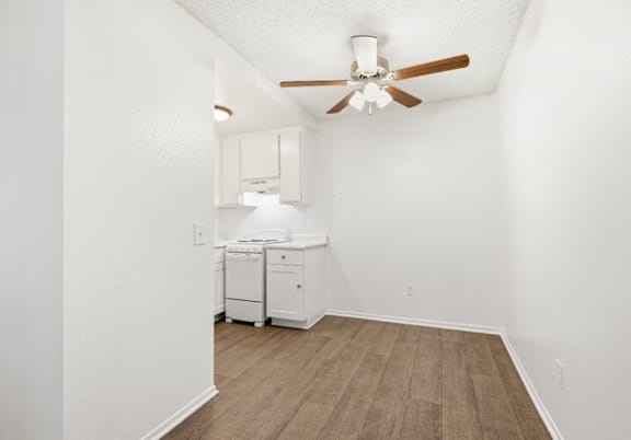 A white room with a ceiling fan and a wood floor.
