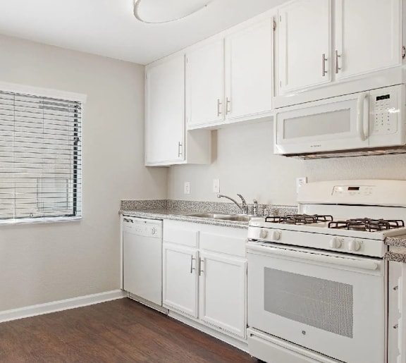 A white kitchen with a stove, oven, dishwasher, and microwave.