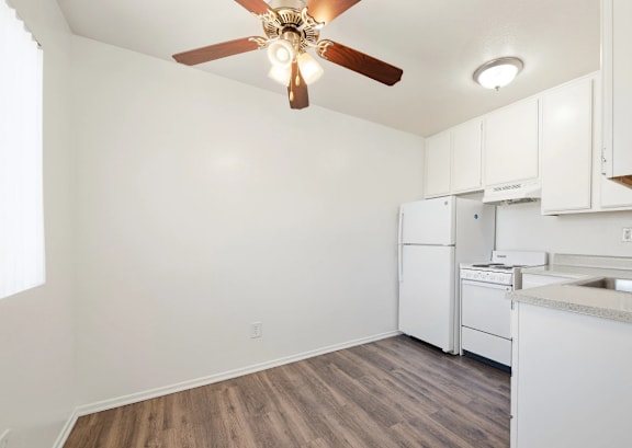 A kitchen with white cabinets and a ceiling fan.