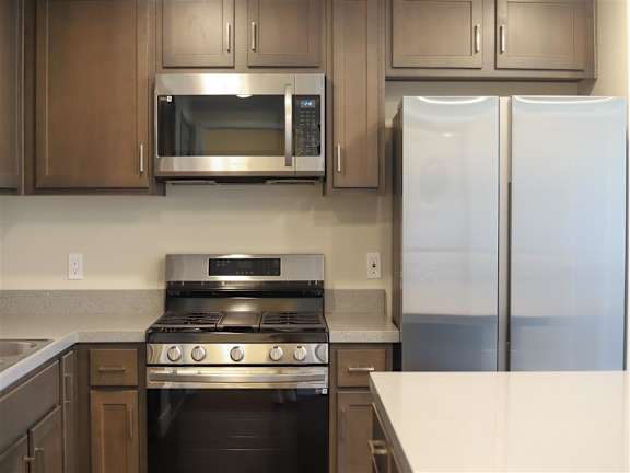 a kitchen with a stove refrigerator and microwave at Loma Villas Apartments, California