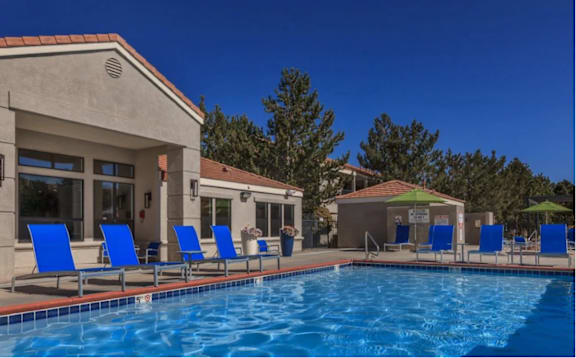 A pool with blue chairs and a building in the background.