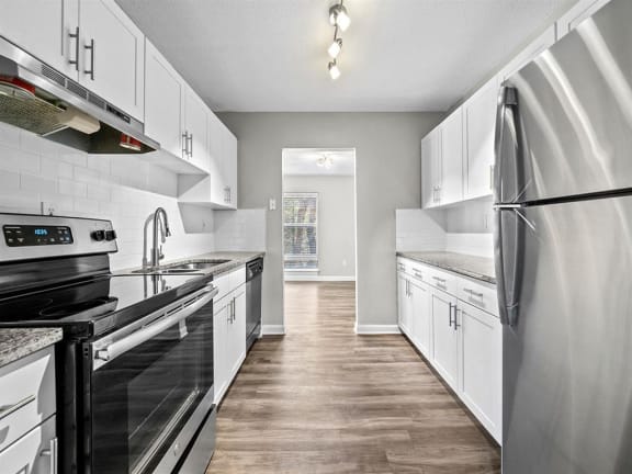 a kitchen with stainless steel appliances, granite countertops, and white cabinets