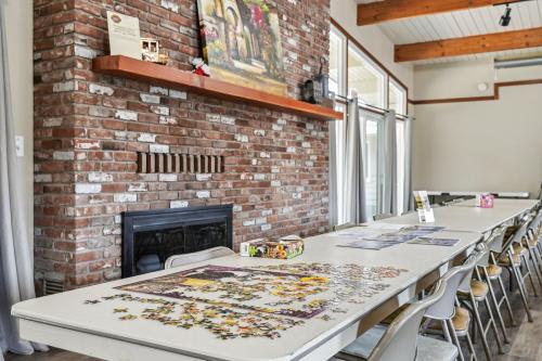 A jigsaw puzzle is being assembled on a table in a room with a brick fireplace.