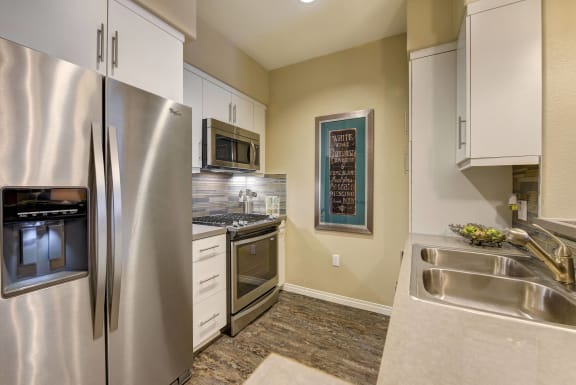 Kitchen with stainless steel appliances and white cabinets at Avino in San Diego