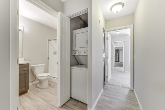 a renovated bathroom with a closet and a toilet and a hall way to a kitchen