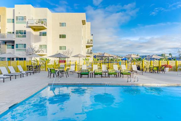 A pool area with sun loungers and a building in the background.