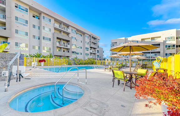 A swimming pool area with a yellow umbrella and chairs.