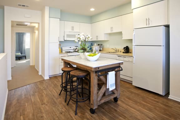 a kitchen with white cabinets and a wooden island with stools
