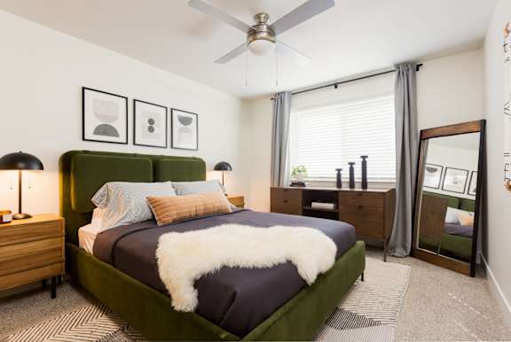 A bedroom with a green bed and a ceiling fan.