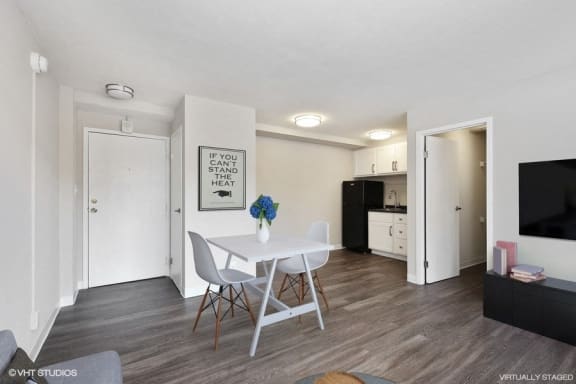 a studio apartment with a white table and chairs and a kitchen in the background