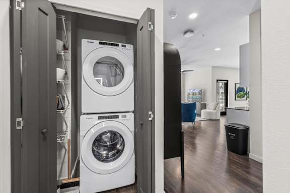 A modern laundry room with a washer and dryer built into a cabinet.