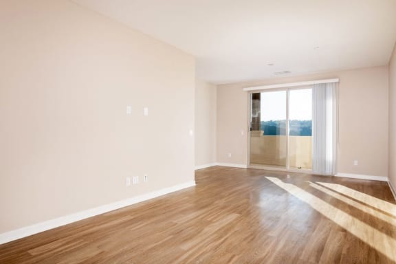 an empty living room with wood floors and a glass door