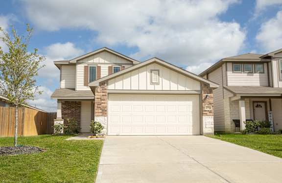 A white garage door is in the center of a driveway at The Village at Caney Mills, Conroe